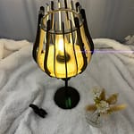 Lampe sur pied en bois Leo sur une nappe en velour à côté d'un oiseau en 3D et d'un vase