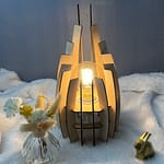 Lampe en bois dubaï, couleur brute avec sa propre ampoule. Posée sur une nappe en velour à côté d'un lapin 3D et d'un vase avec des fleurs en bois