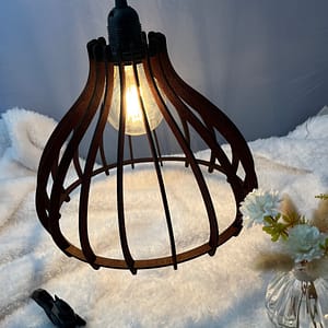 Suspension en bois Boréa couleur acajou, avec on ampoule allumé. Disposée au-dessus d'une nappe en velour et à côté d'un écureuil en 3D et d'un vase en verre