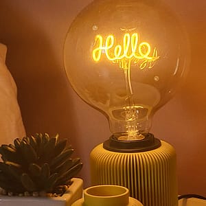 Lampe Solelight en 3D avec ampoule hello jaune sur une table basse de chambre accompagné d'un petit vase solea. Idéal comme lumière d'appoint.