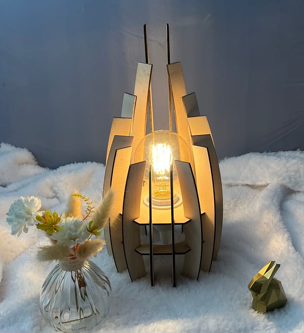 Lampe en bois dubaï, couleur brute avec sa propre ampoule. Posée sur une nappe en velour à côté d'un lapin 3D et d'un vase avec des fleurs en bois