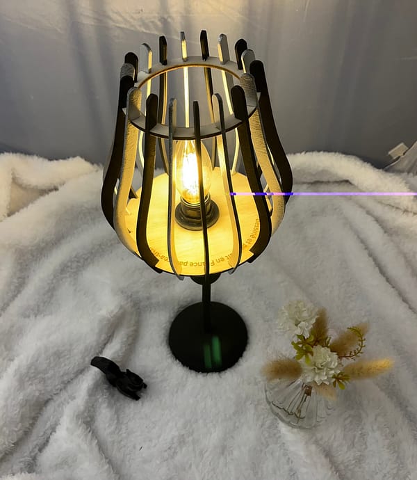 Lampe sur pied en bois Leo sur une nappe en velour à côté d'un oiseau en 3D et d'un vase